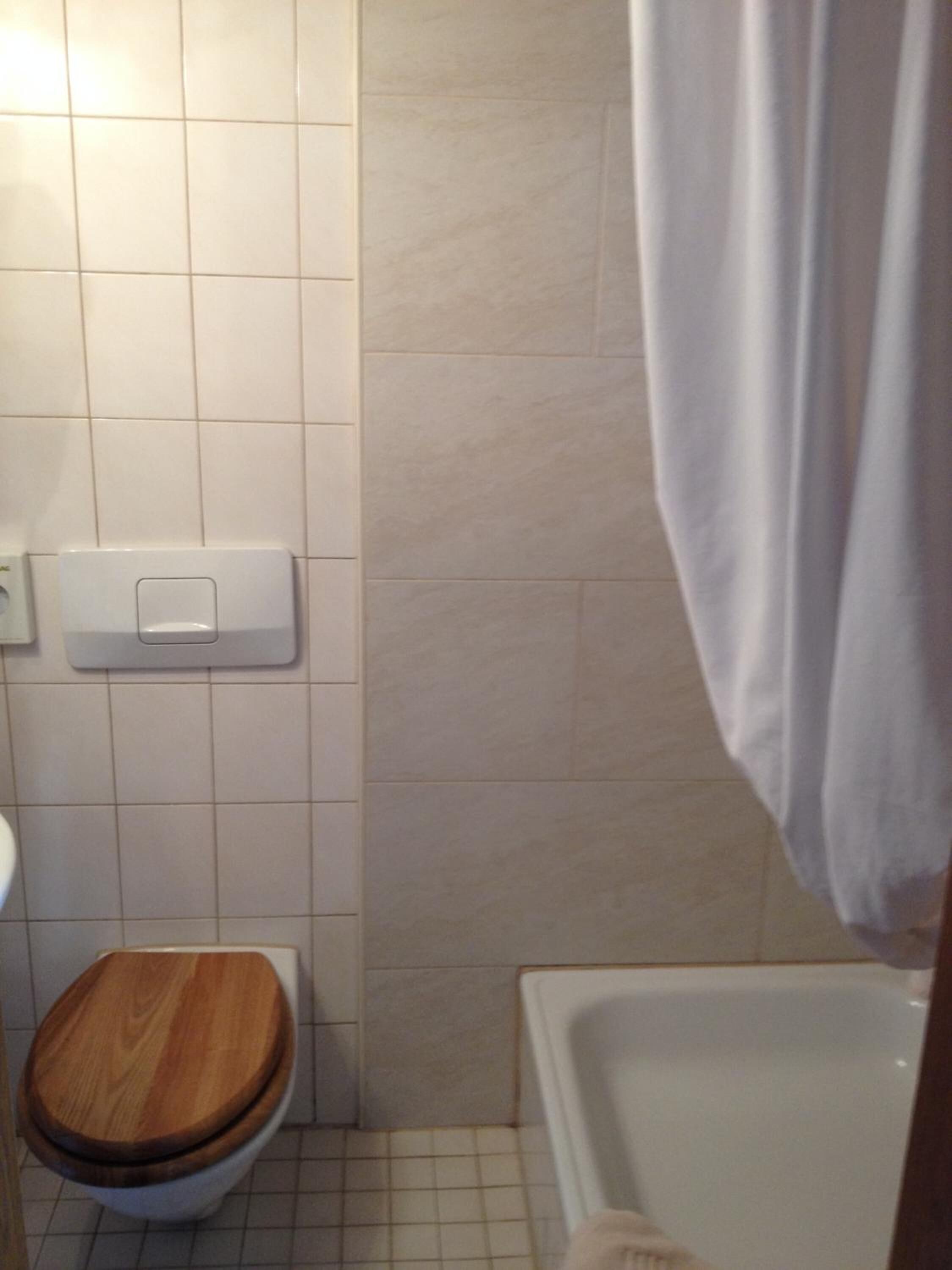 Een badkamer met toilet, bad en douchegordijn.