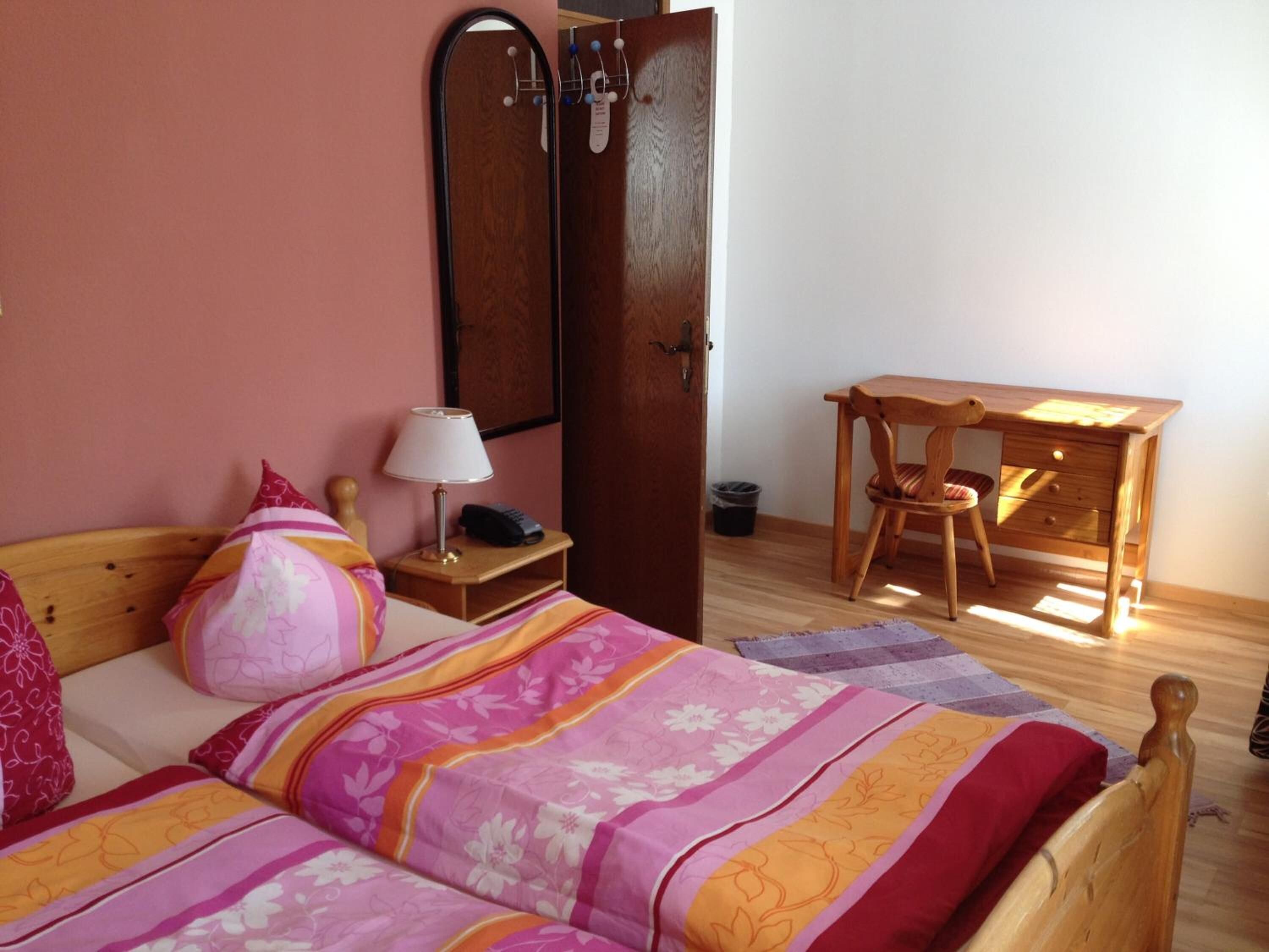 A bedroom with a bed, a desk, and a chair.