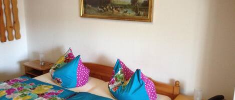 A bedroom with a bed, a painting on the wall, and a bedside table with a lamp and a phone.