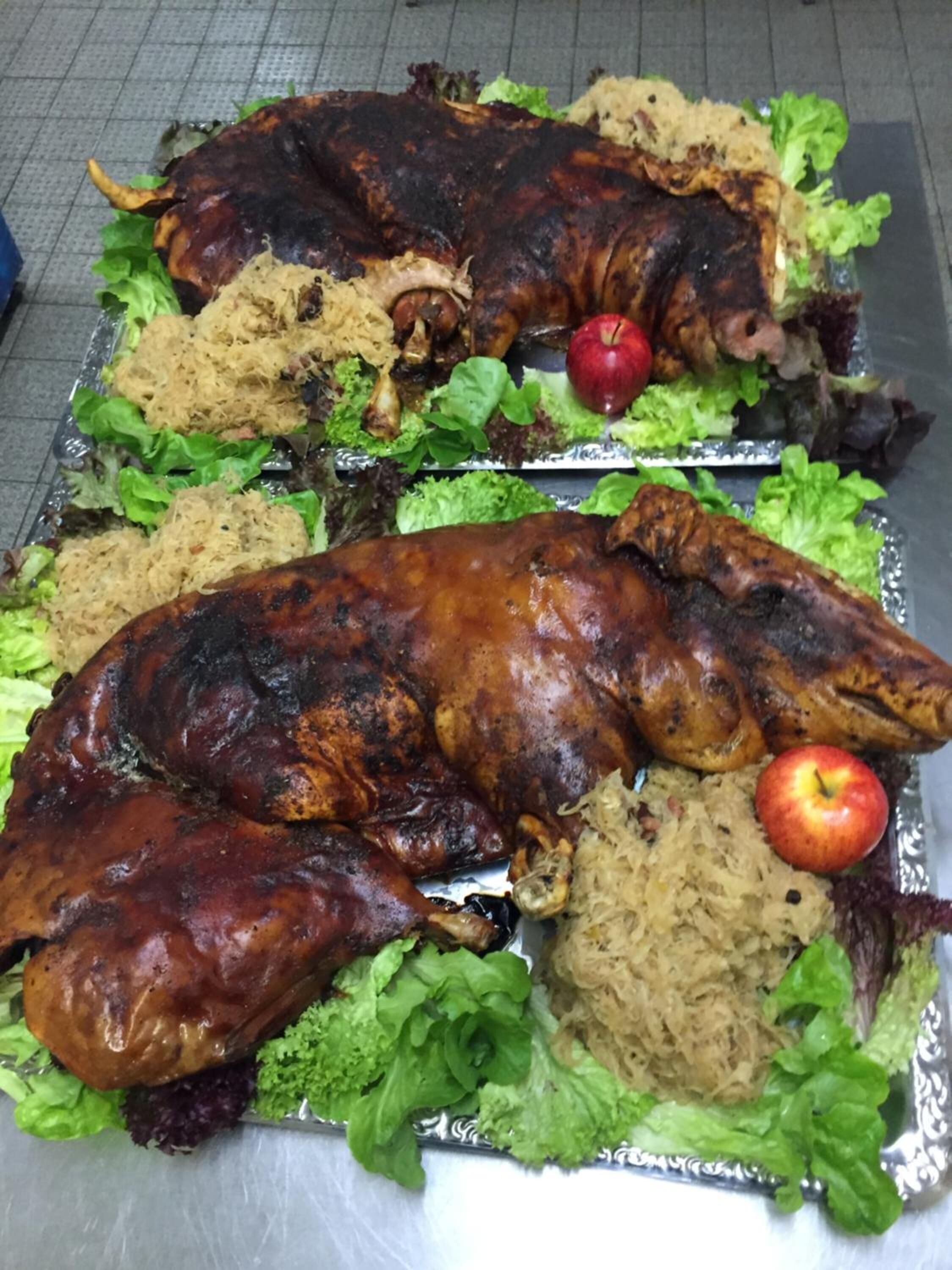 Un cerdo asado en una bandeja con lechuga y una manzana.