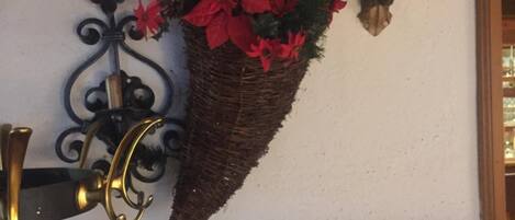 A wall-mounted decorative piece with a basket of red poinsettia flowers, a mounted skull, and a mounted deer head.