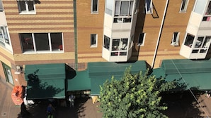 A multi-story building with a brick facade, multiple windows, and a green awning.