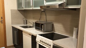 A compact kitchen with a microwave, stove, and sink.