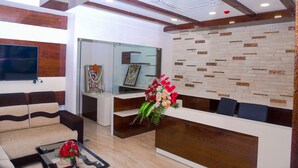 A modern reception area with a sofa, a reception desk, and a TV mounted on the wall. - Hotel Blue Ocean Residency (Bengaluru)