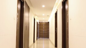 A long, well-lit hallway with shiny tiled floors and wooden doors on both sides. - Hotel Blue Ocean Residency (Bengaluru)