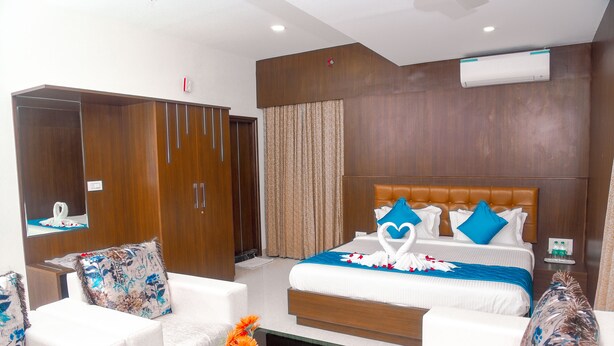 A hotel room with a large bed, a sofa, a coffee table, and a wardrobe. - Hotel Blue Ocean Residency (Bengaluru)