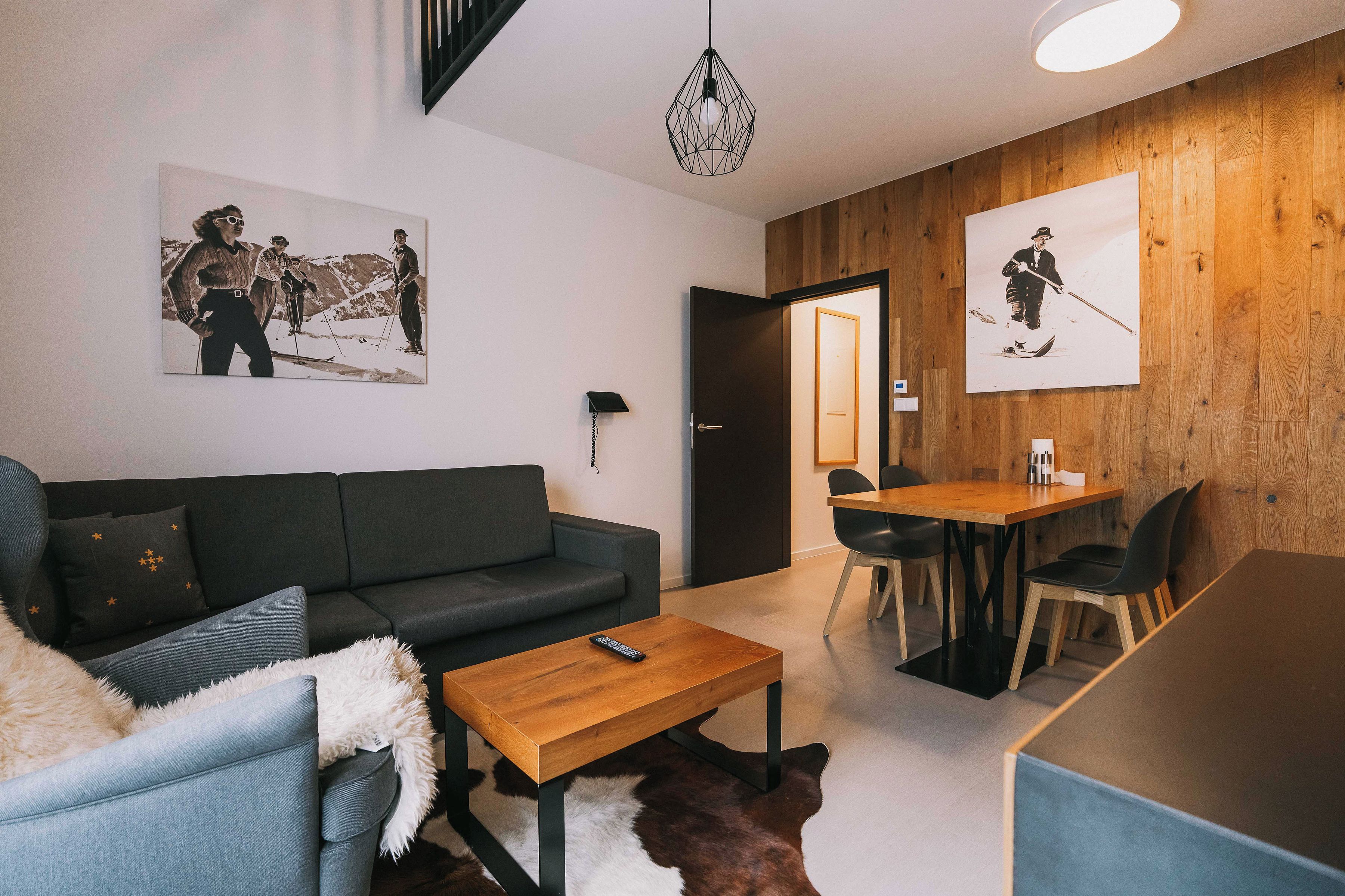 A modern living room with a sofa, a coffee table, and a dining area with chairs and a table.