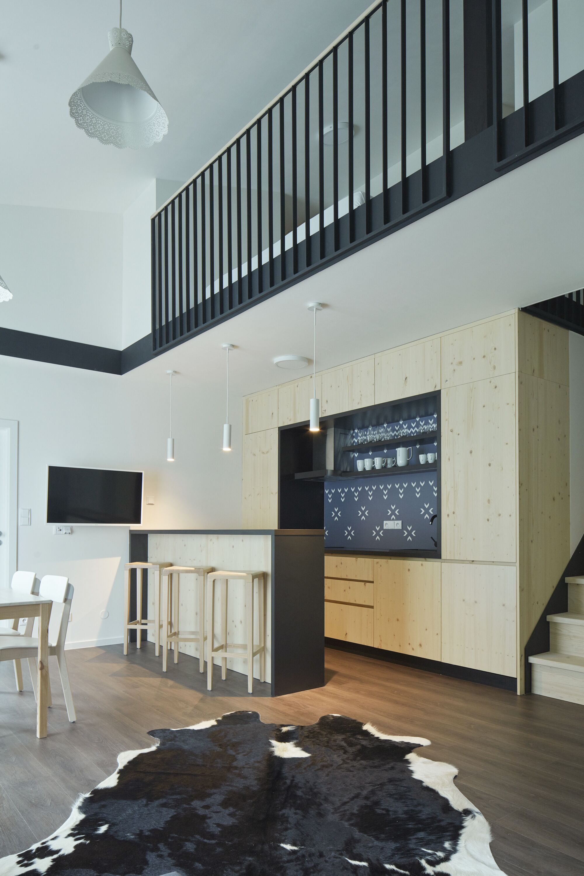 A modern kitchen with wooden cabinets, a central island, and a black and white cowhide rug.