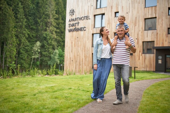 A family walking on a path in front of a building with a sign reading "APARTHOTEL SVATÝ VAVRINEC". - Aparthotel Svatý Vavřinec (Pec pod Snezkou)