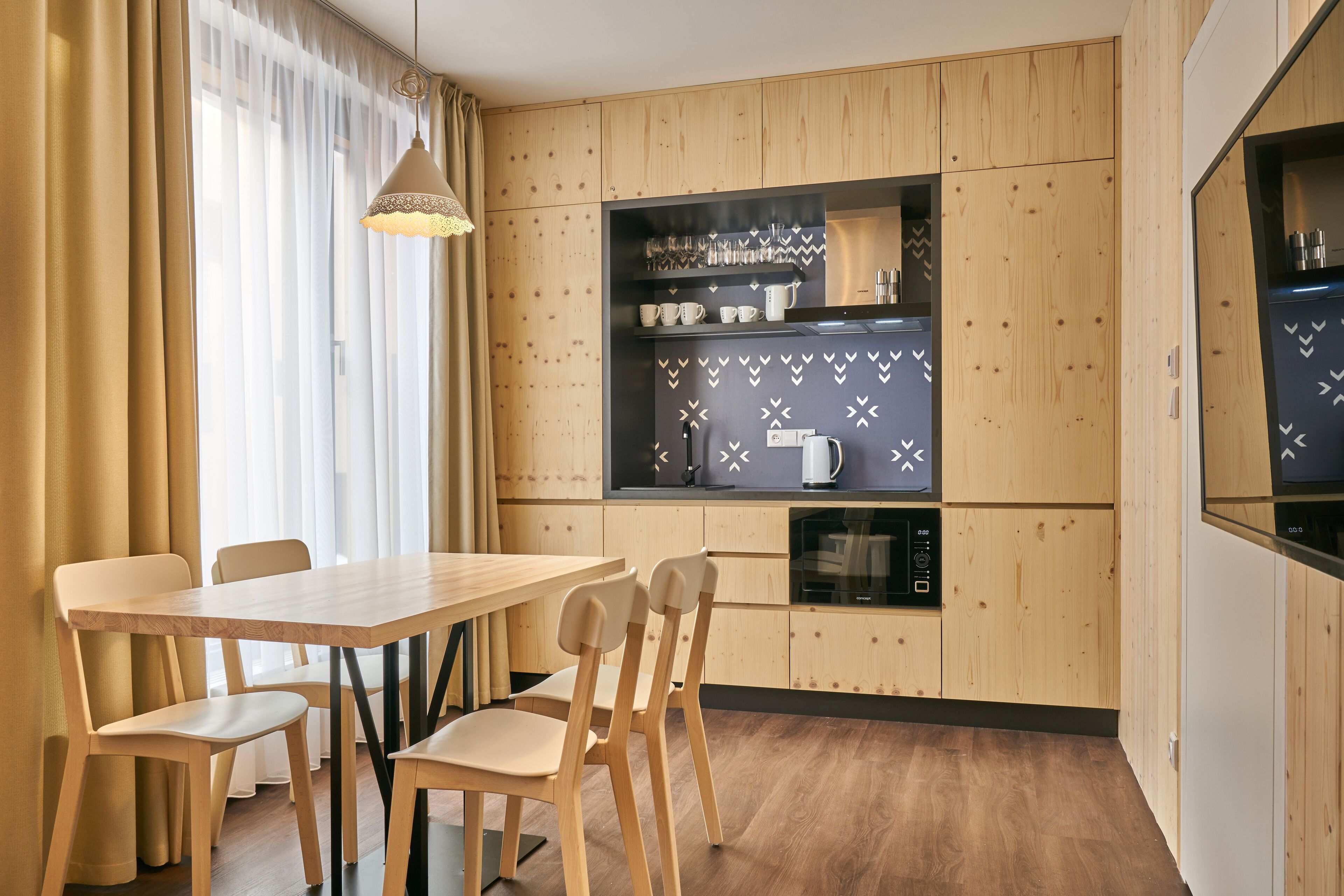 A modern kitchen with wooden cabinetry, a built-in microwave, and a dining area with a wooden table and chairs.