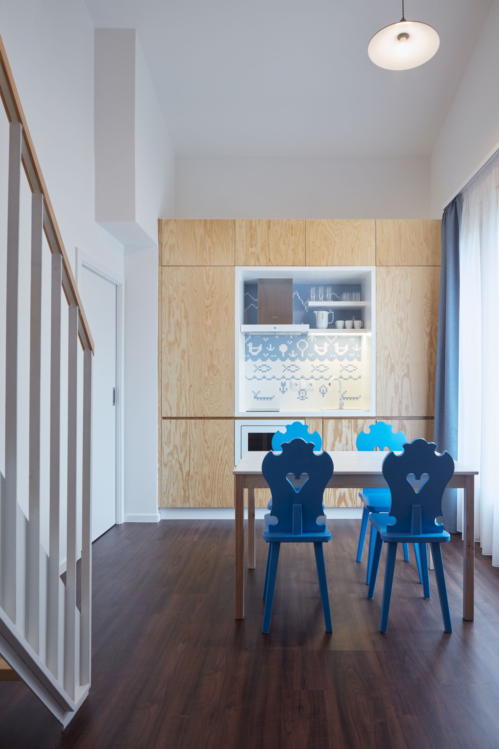 Una cocina moderna con armarios de madera, una encimera blanca y dos sillas azules con forma de corazón.