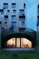 Un edificio moderno con un balcón curvo y zona de estar al aire libre.