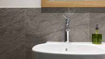 A bathroom with a white sink, chrome faucet, and a green soap dispenser.