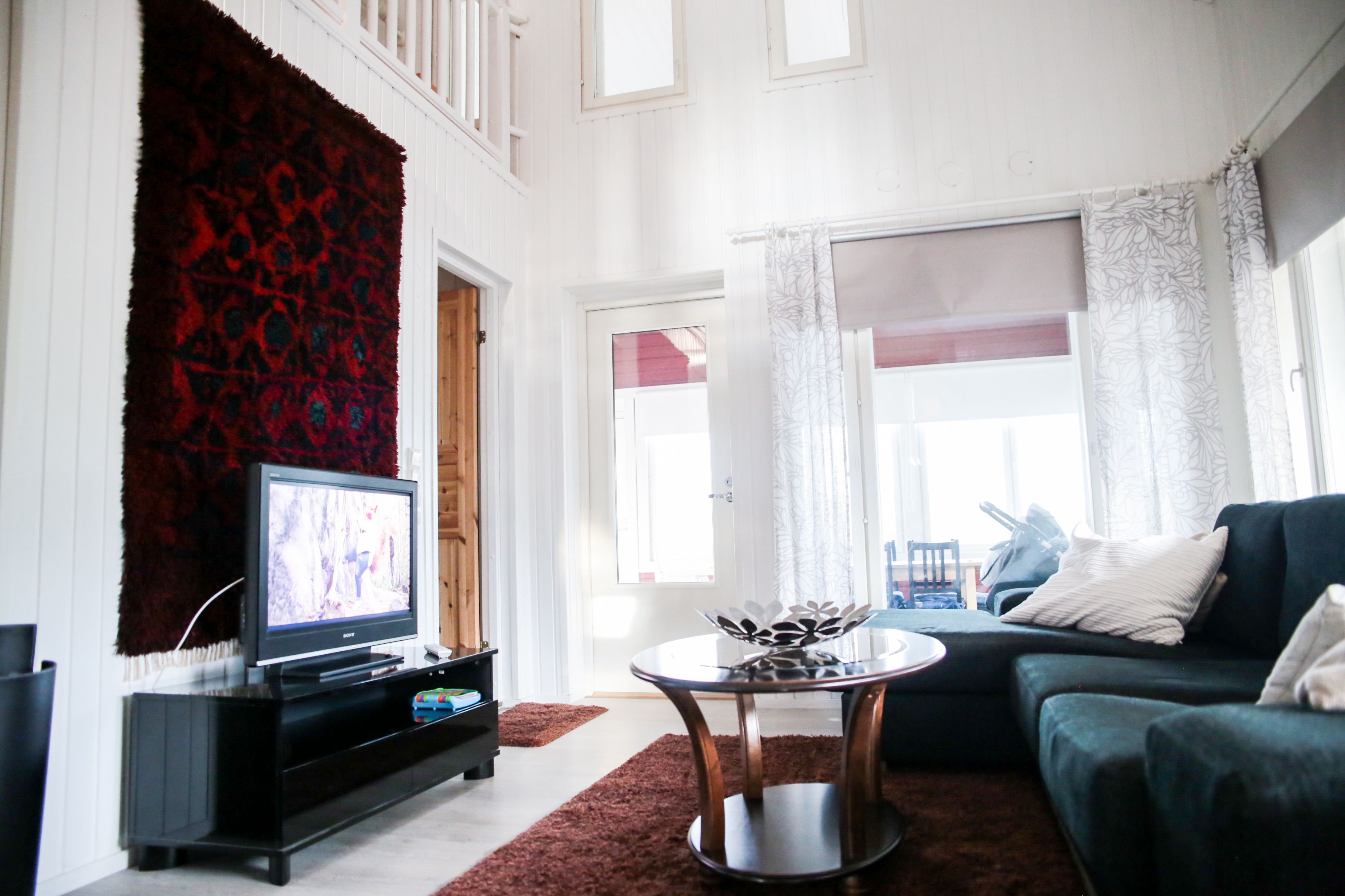 A living room with a television, a sofa, a coffee table, and a red carpet.