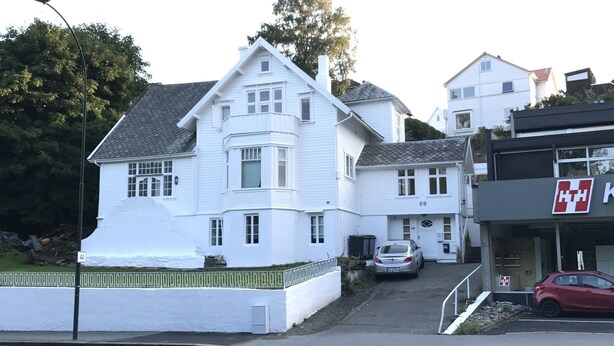 A white two-story house with a garage, a street lamp, and a parked car.