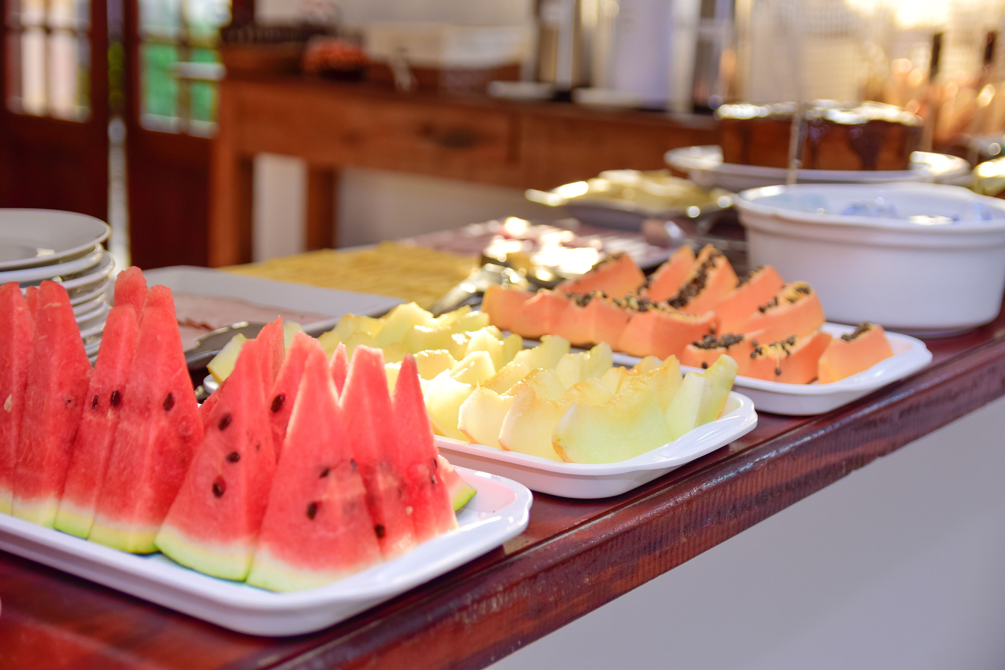 Un tavolo del buffet con diversi vassoi di frutta, tra cui anguria, ananas e melone.
