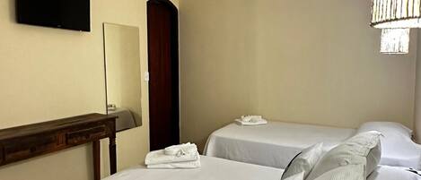 Habitación de hotel con dos camas, una mesita de noche de madera, un televisor de pantalla plana, un espejo, una araña y una puerta de madera.