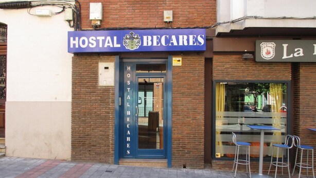 A HOSTAL BECARES building with a blue entrance, a signboard, and a visible window. - Hostal Becares (Palencia)