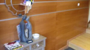 A room with a wooden wall, a small table with a kettle, a cup, and some magazines. - Hostal Becares (Palencia)
