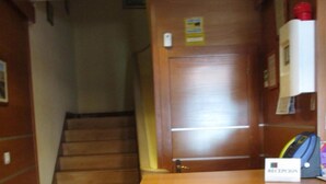 A reception desk with a sign reading "RECEPCION" in a hallway with wooden walls and a staircase. - Hostal Becares (Palencia)