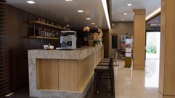 A reception area with a marble counter, bar stools, and a coffee machine.