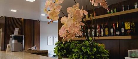 A reception area with a marble counter, potted plants, and a shelf with various items.