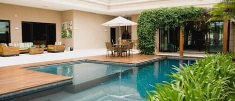 Una piscina al aire libre, sillones reclinables de piscina