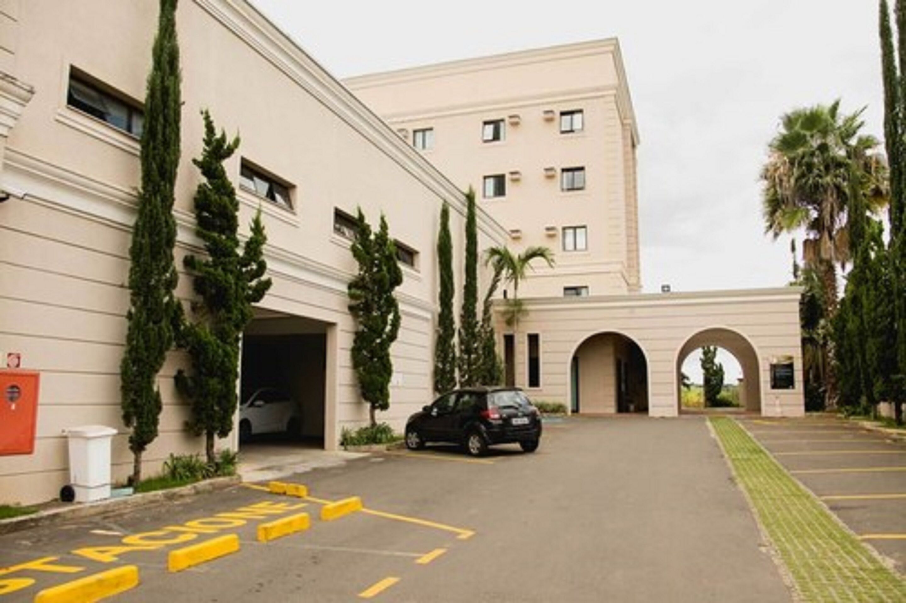Un edificio con zona de estacionamiento, un coche y un sendero para peatones.