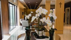A modern lobby with a glass table, white orchids, and a cross on the wall. - Class Hotel Alfenas (Alfenas)
