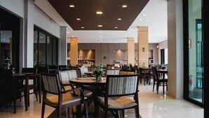 A modern dining area with multiple tables and chairs, a kitchen in the background, and a large glass door on the right. - Class Hotel Alfenas (Alfenas)