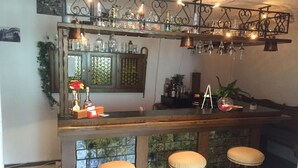 Una zona de bar con taburetes, estantes con botellas e iluminación decorativa.