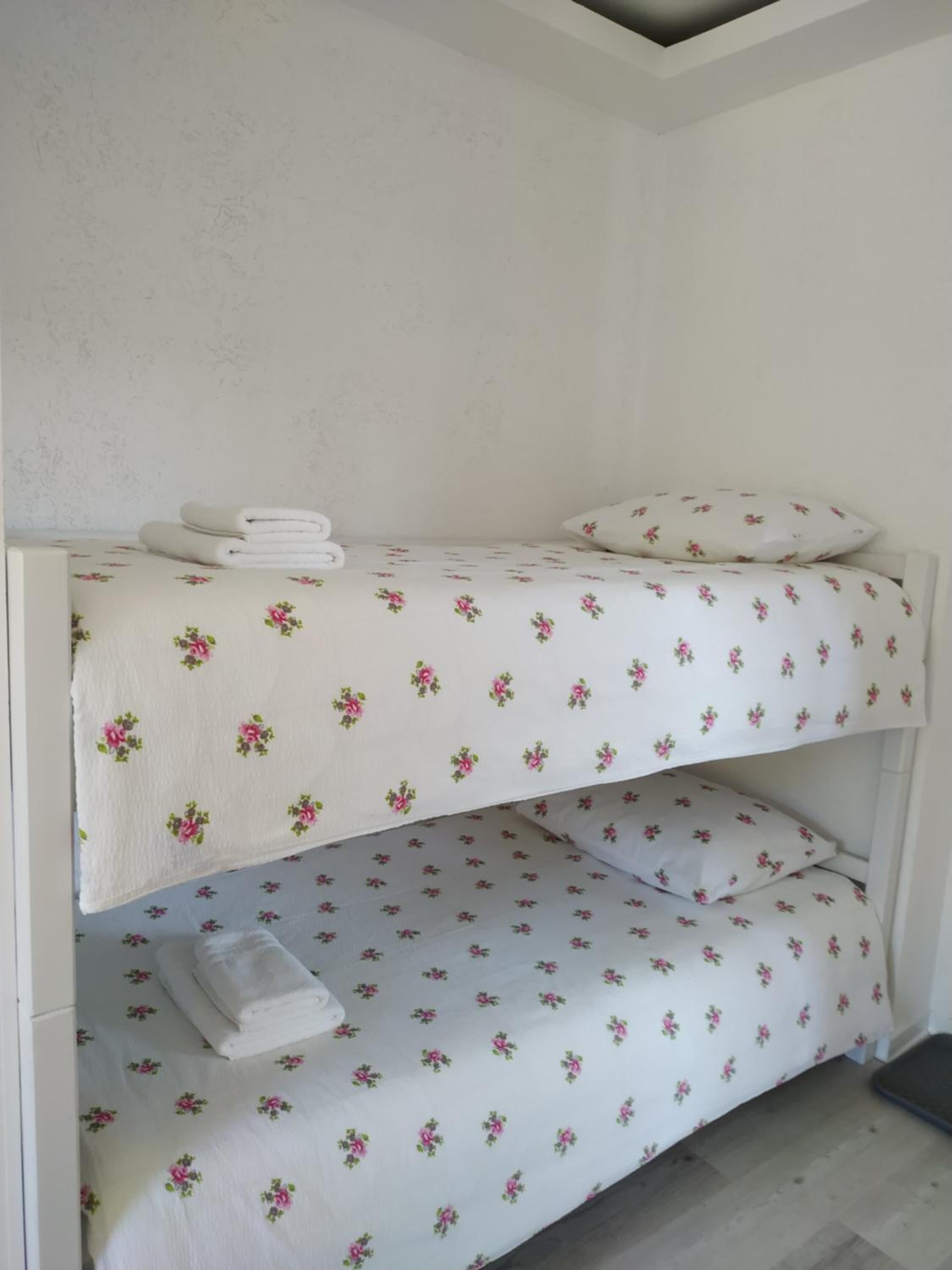 Ein Stockbett mit blumigem Bettzeug und ordentlich gefalteten Handtüchern.