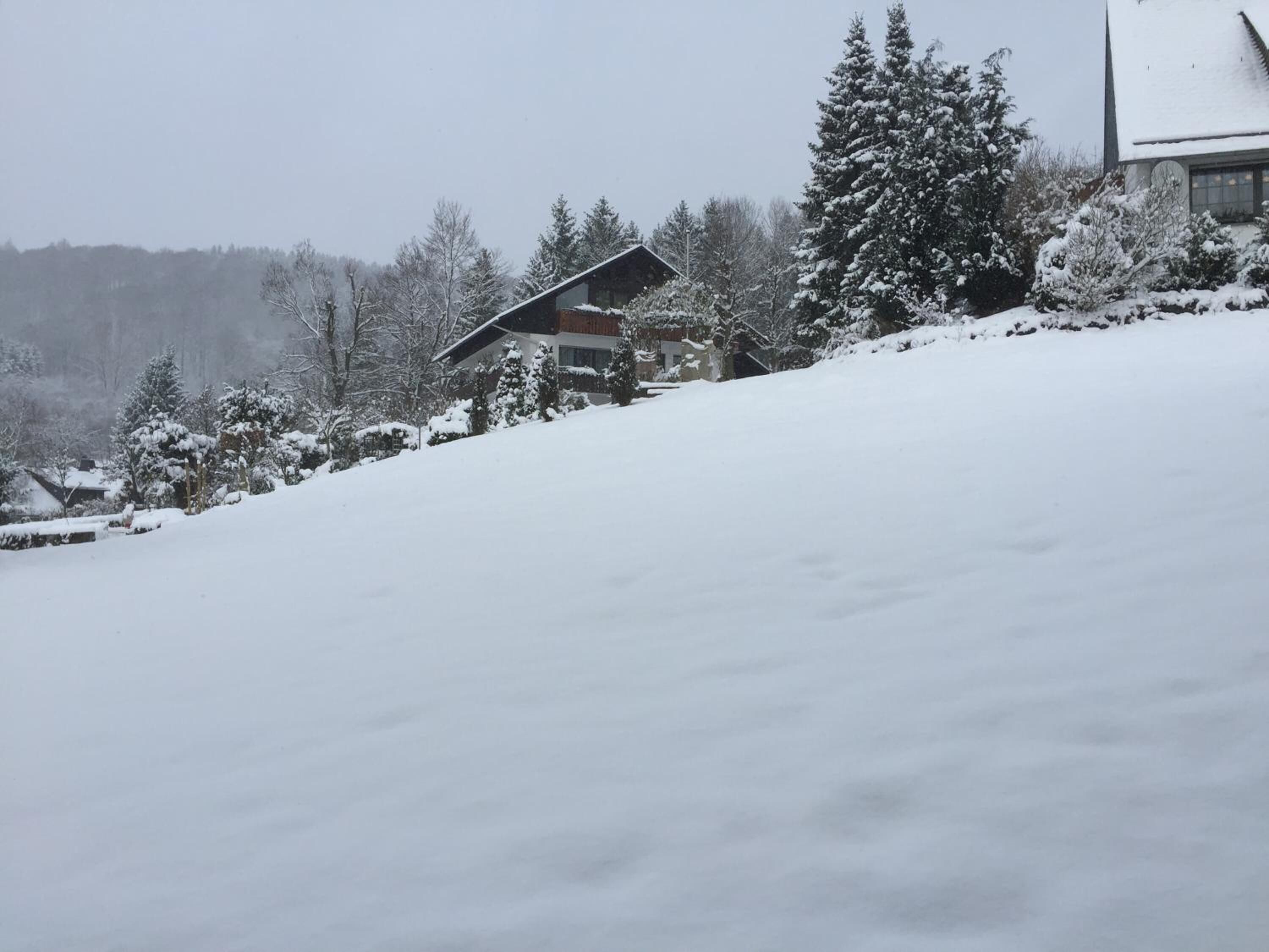 Schneebedeckte Landschaft mit einem Gebäude, das ein geneintes Dach und ein Fenster hat.
