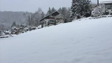 Schneebedeckte Landschaft mit einem Gebäude, das ein geneintes Dach und ein Fenster hat.