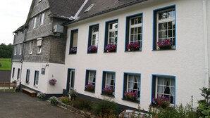 Un edificio de dos pisos con numerosas ventanas, algunas con jardineras.
