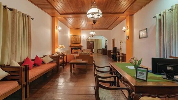 A cozy living room with wooden furniture, a dining area with a table and chairs, and a television on the desk. - Avian Breeze (Nuwara Eliya)