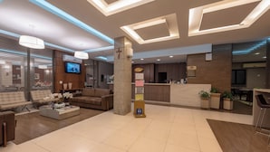 A modern lobby with a reception desk, seating area, and a television screen. - Class Hotel Passos (Passos)