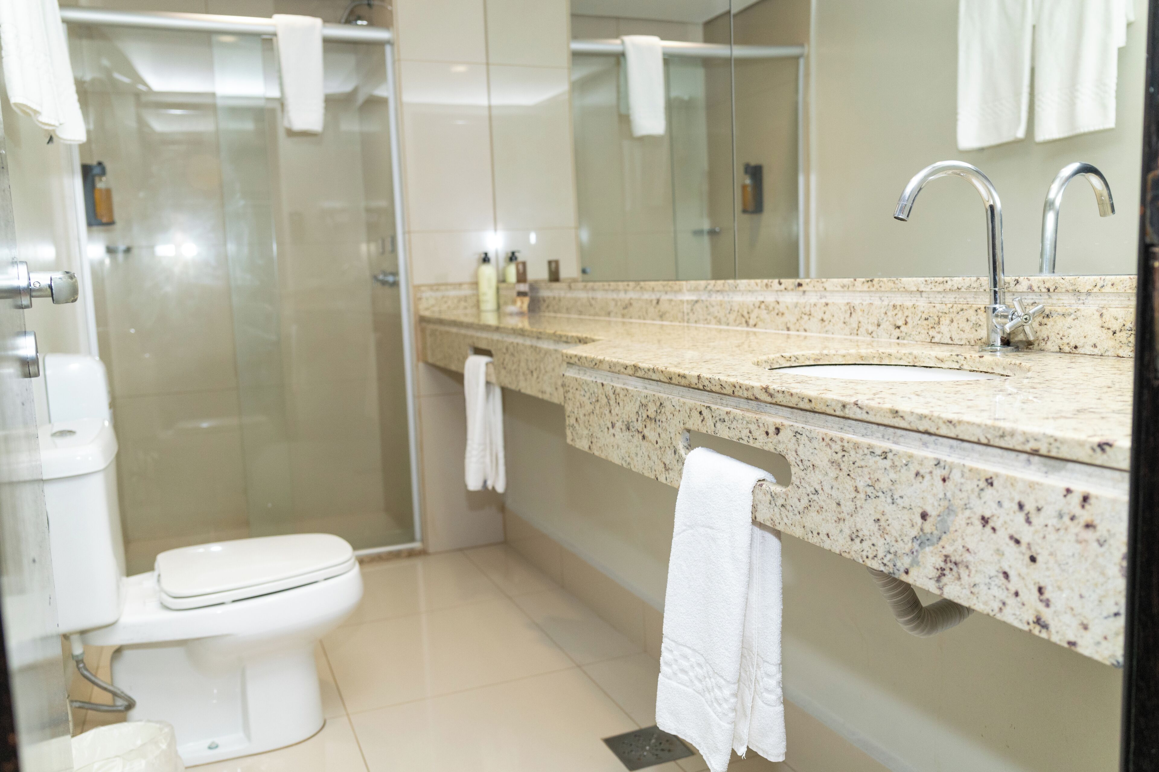 Un bagno con un water, un lavandino, una doccia e uno specchio.