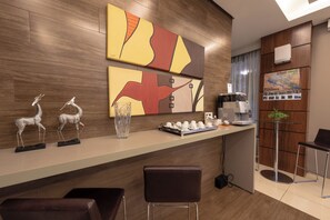 Un moderno vestíbulo de hotel con mostrador de recepción, zona de estar y una máquina de café.