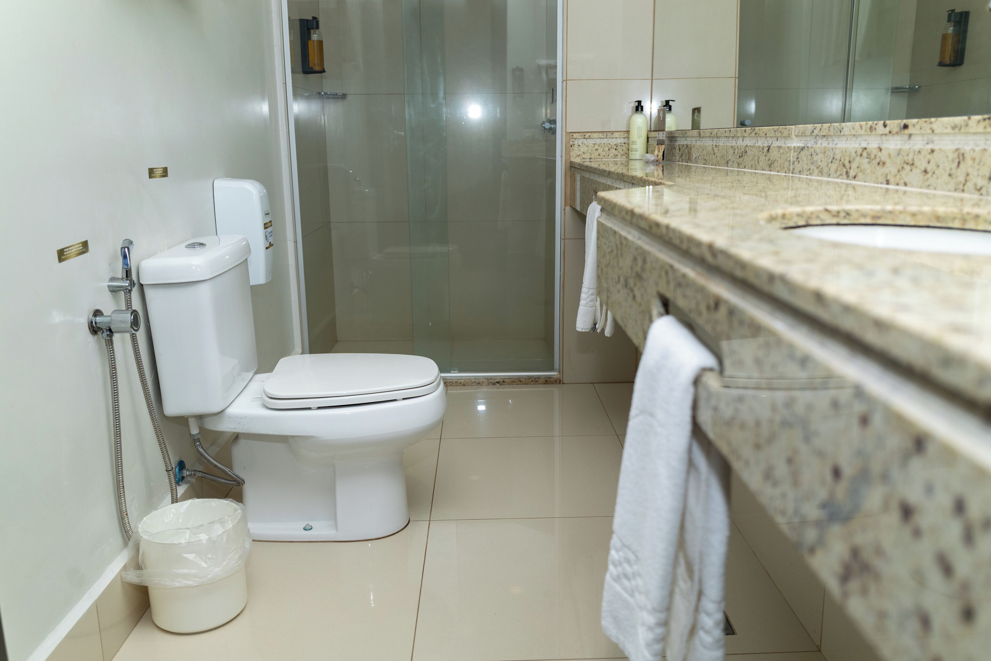 Un baño con inodoro, ducha y lavamanos, con una toalla colgada en la pared.