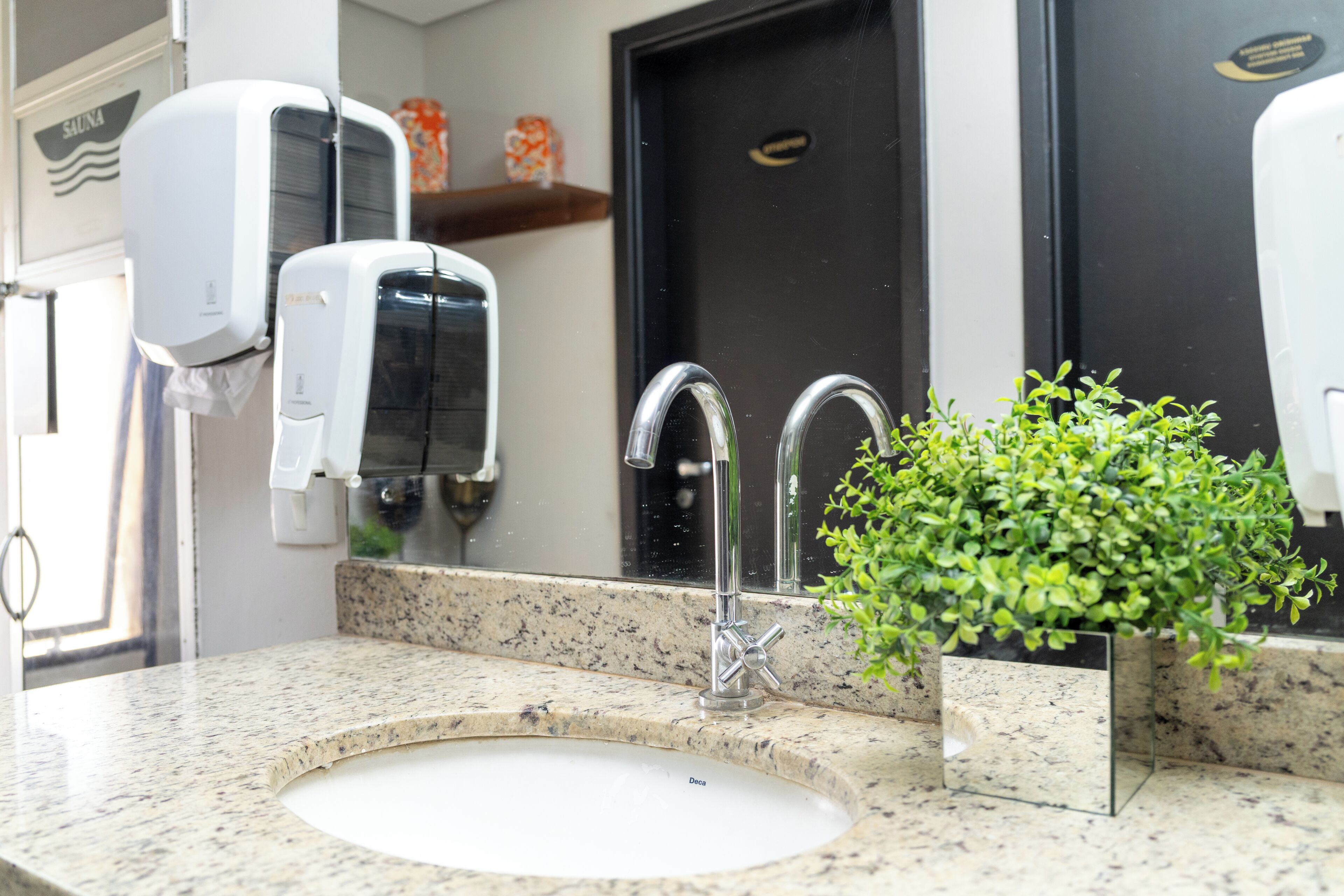 A bathroom with a sink, a mirror, a faucet, and a soap dispenser.