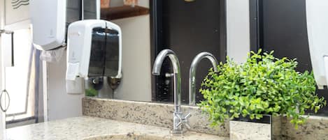 A bathroom with a sink, a mirror, a faucet, and a soap dispenser.