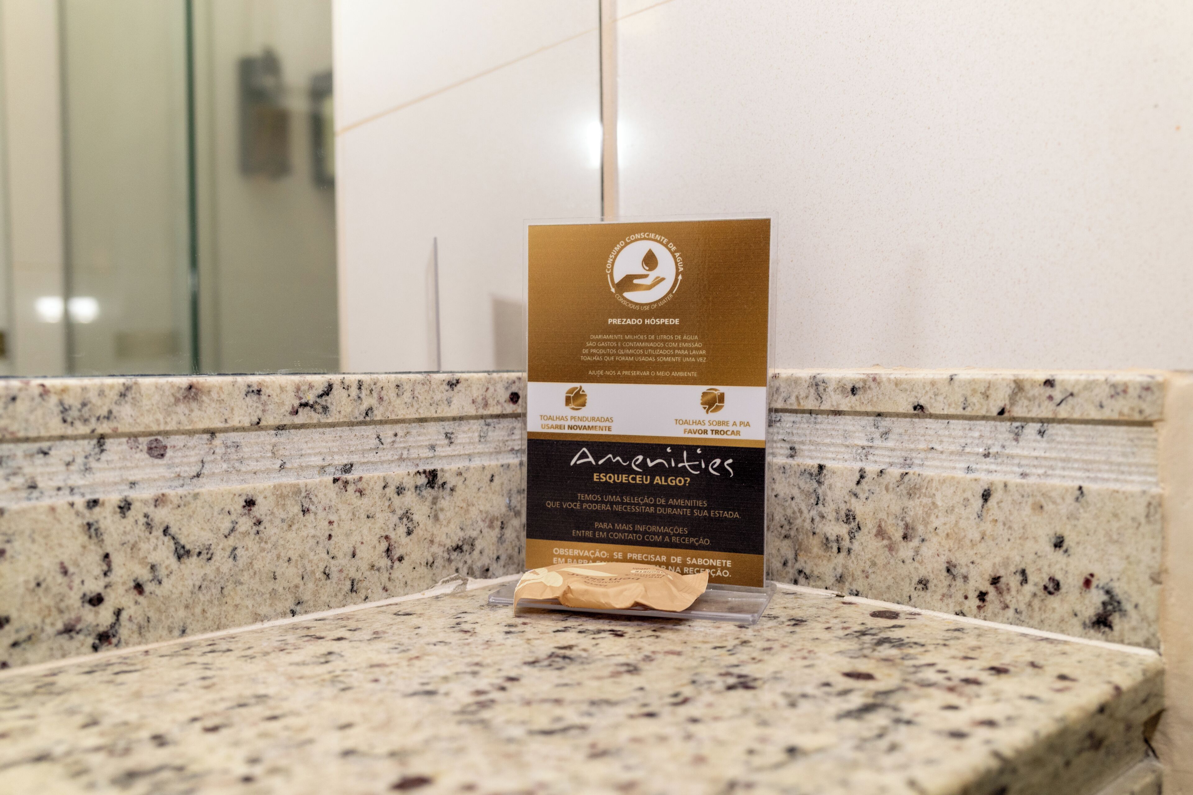 A sign on a granite countertop with a message about water conservation and amenities.