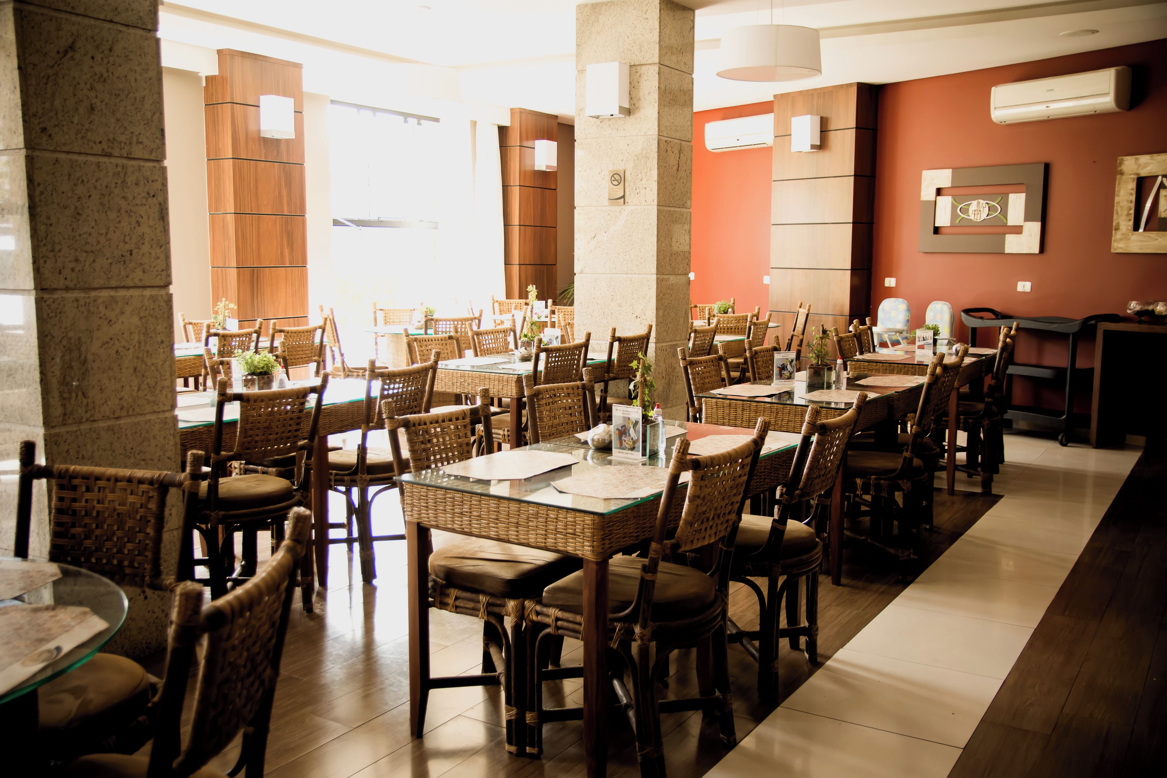 A restaurant with multiple tables and chairs, a stone pillar, and a wall-mounted air conditioning unit.