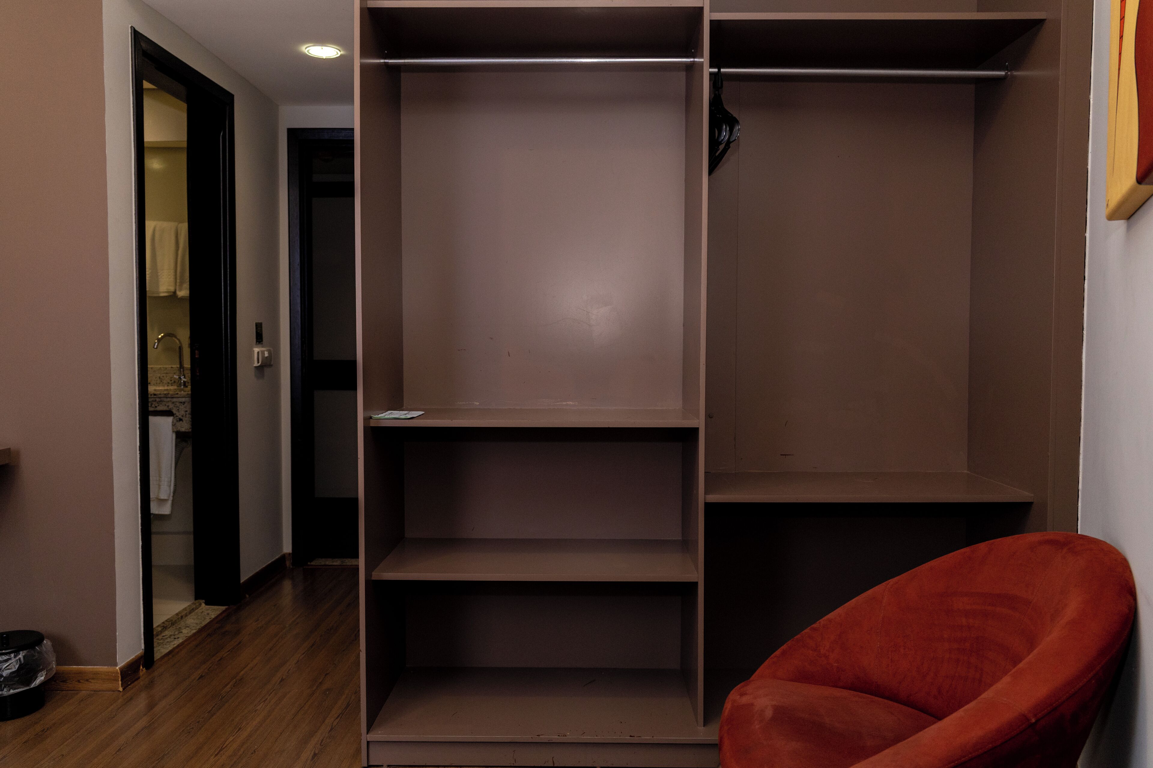 A walk-in closet with multiple shelves and a red chair.