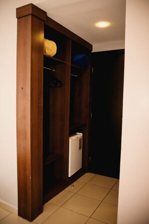Ein kleines Zimmer mit einem Holzschrank, einem weißen Gerät und einem Fliesenboden.