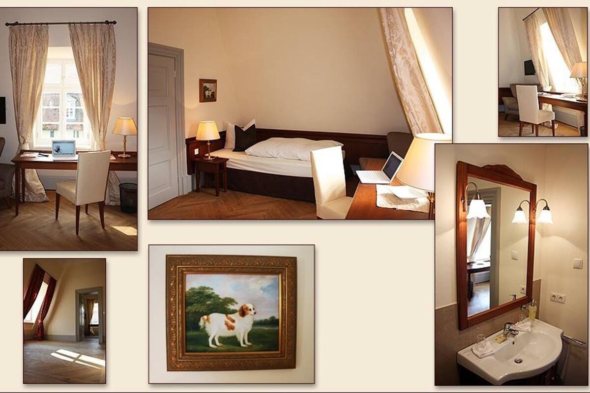 Een hotelkamer met een bed, bureau, stoel en een lijst met een afbeelding van een hond.