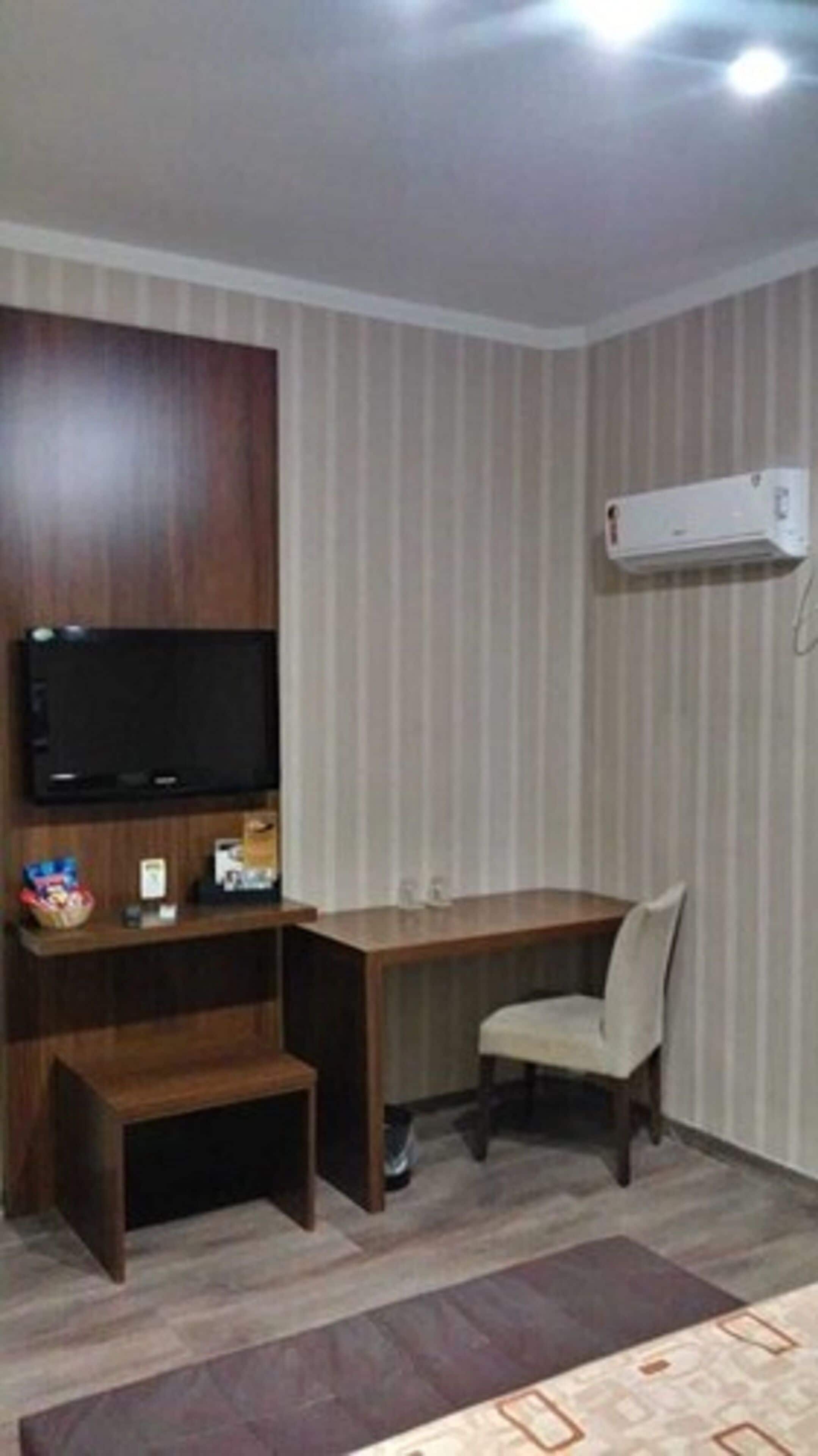 Une pièce avec un bureau en bois, une télévision et une chaise.