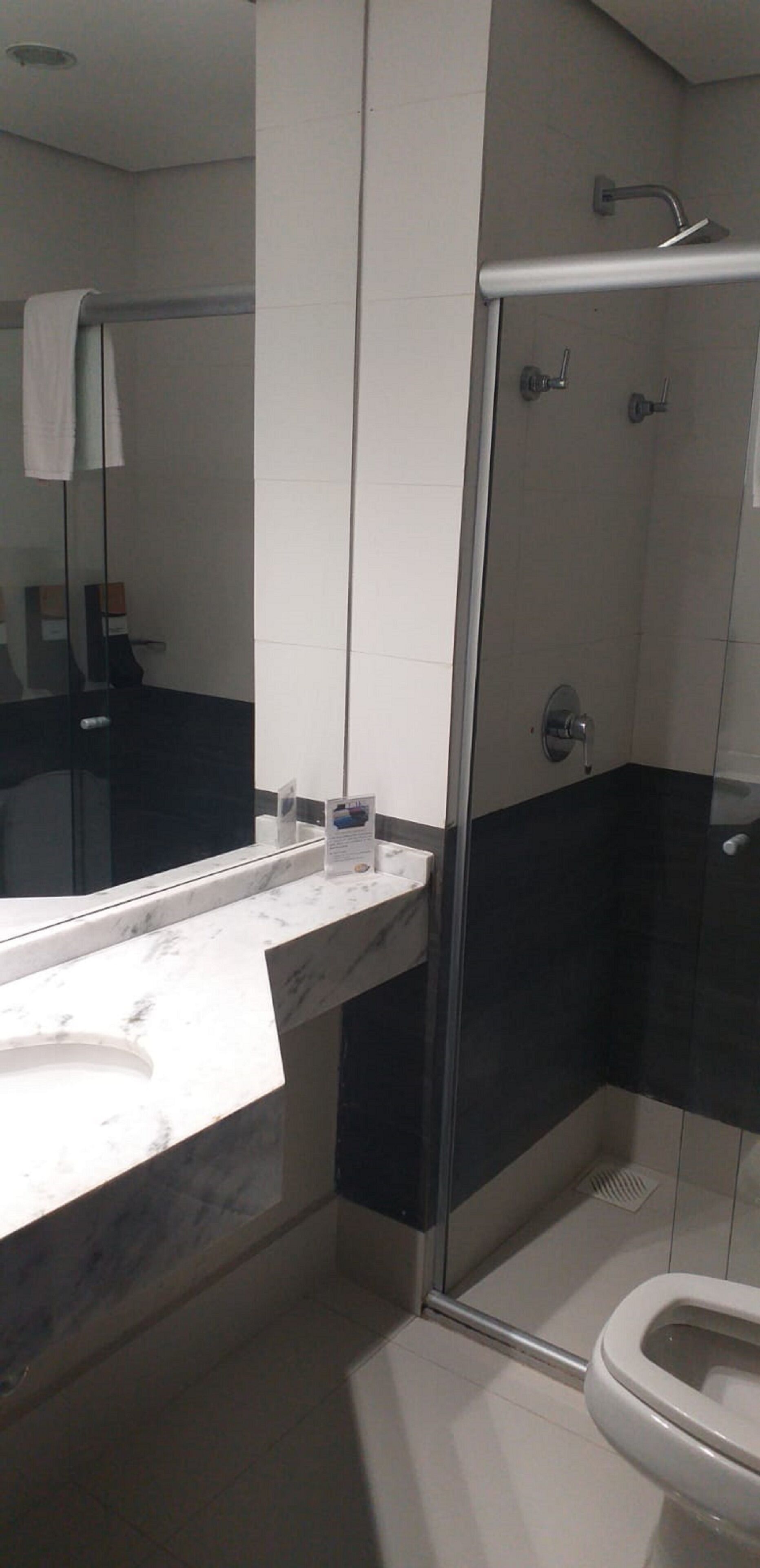 Un baño moderno con ducha de vidrio, lavamanos de mármol y retrete.