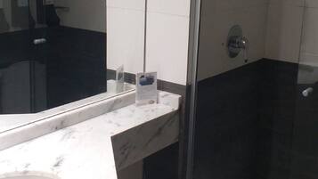 Un baño moderno con ducha de vidrio, lavamanos de mármol y retrete.